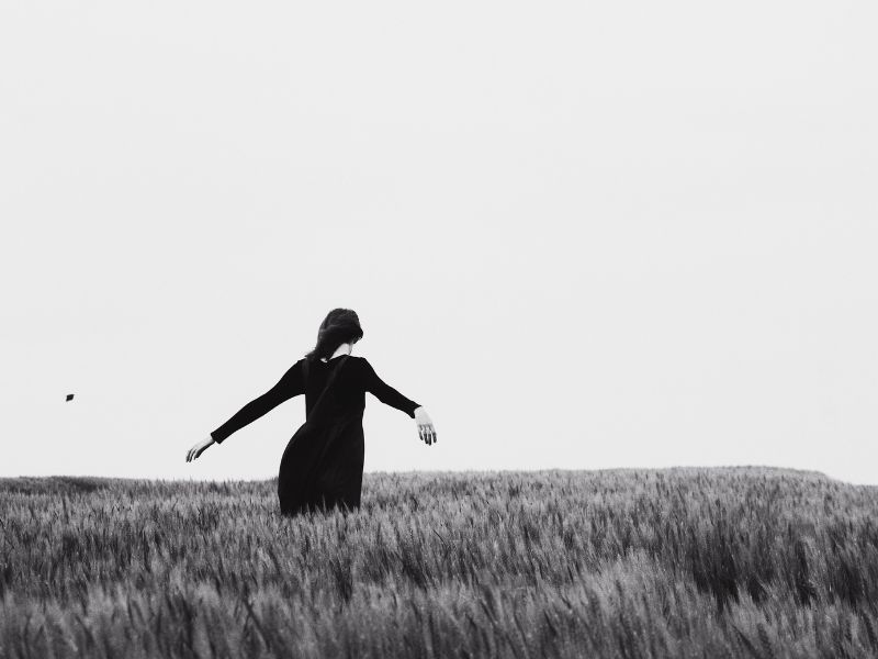 A woman in a long sleeved long dress is walking alone in a grassy field. Photo by fall maple: https://www.pexels.com/photo/woman-walking-on-the-grass-2339126/