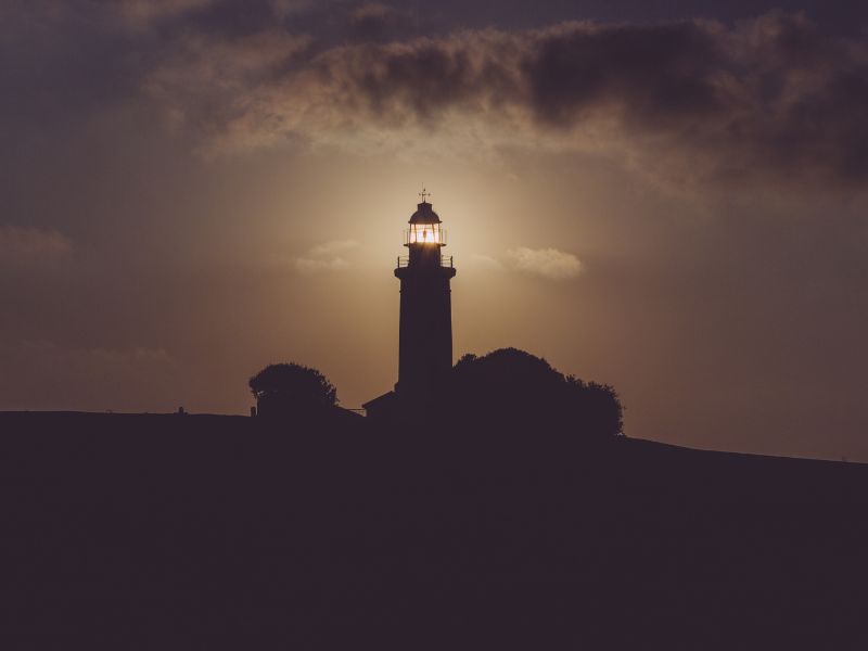 Lighthouse under dark grey skies. Photo by Vlasdislav Dukhin from Pexels.
