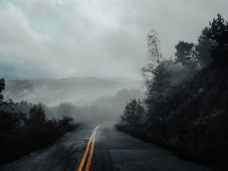 Winding mountain road in foggy twilight. Photo by Tasso Mitsarakis from Pexels.